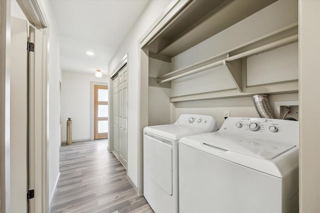 clothes washing area featuring baseboards, light wood-type flooring, and washing machine and clothes dryer