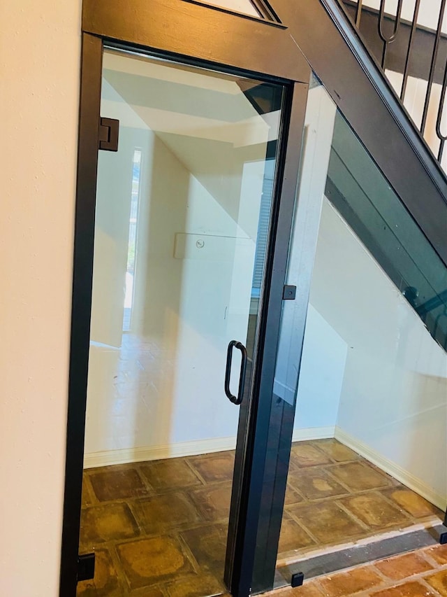 exterior space featuring stone finish floor, elevator, and baseboards