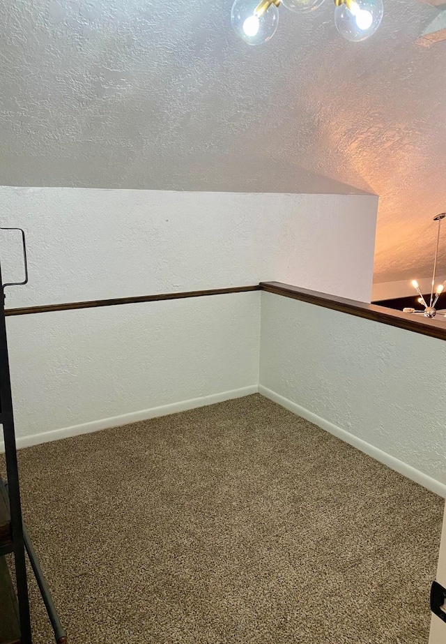 interior space with carpet, baseboards, an inviting chandelier, a textured ceiling, and a textured wall