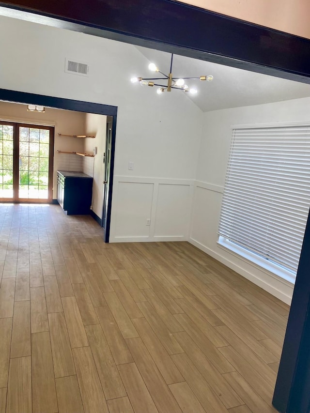 unfurnished room with a chandelier, visible vents, lofted ceiling with beams, and light wood-style floors