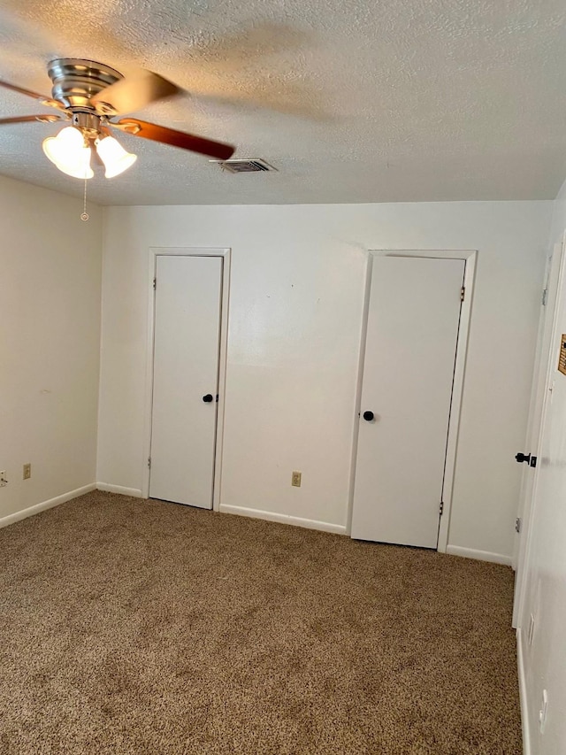 carpeted spare room featuring baseboards, a ceiling fan, visible vents, and a textured ceiling