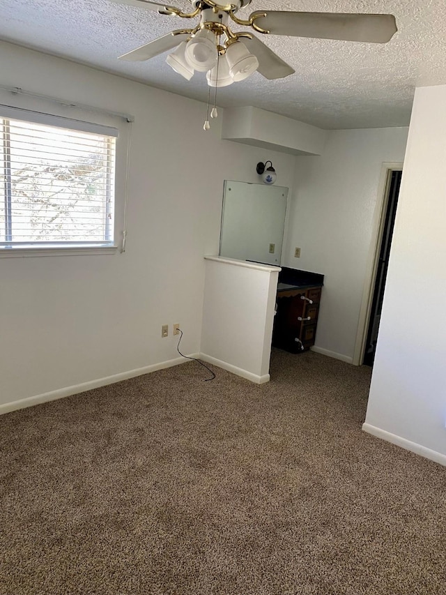 carpeted empty room featuring a ceiling fan, baseboards, and a textured ceiling