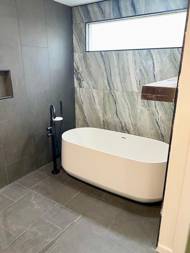 bathroom with tile patterned floors, a soaking tub, and tile walls