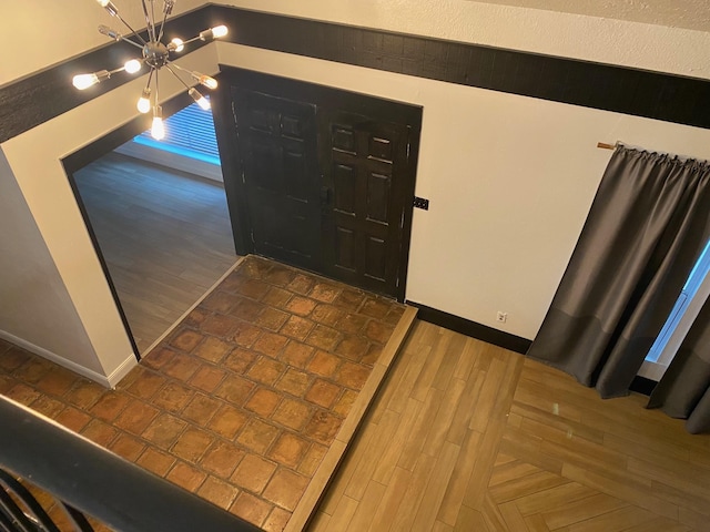 entryway featuring parquet flooring, baseboards, and a chandelier