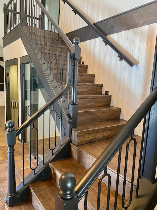 stairway with a high ceiling and wood finished floors