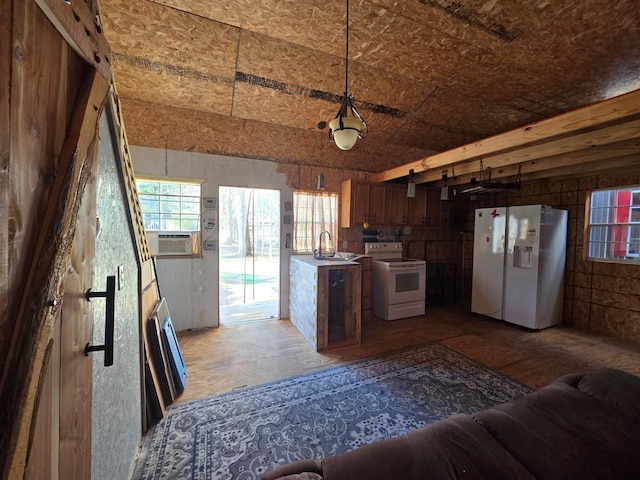 kitchen featuring hanging light fixtures, white appliances, open floor plan, and a sink