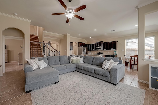 living area featuring arched walkways, stairs, and ornamental molding