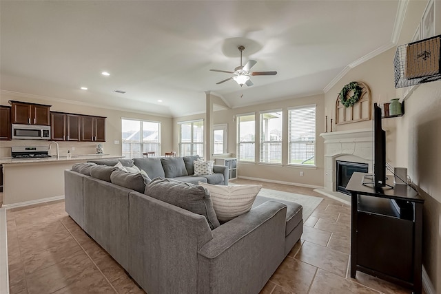 living room featuring a glass covered fireplace, visible vents, crown molding, and baseboards