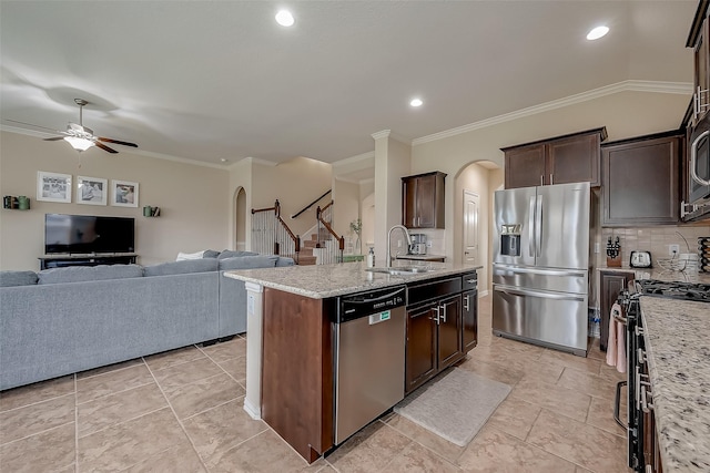 kitchen with a sink, arched walkways, appliances with stainless steel finishes, and open floor plan