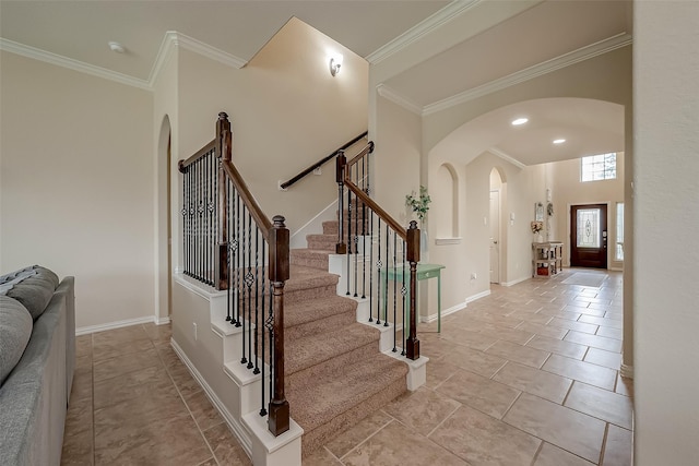 stairs featuring arched walkways, baseboards, crown molding, and a high ceiling