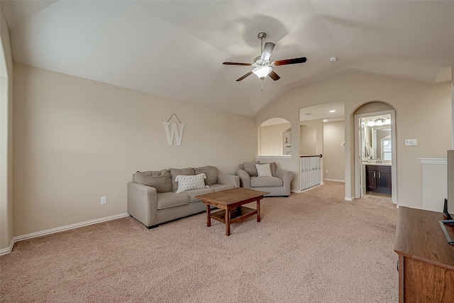 living room featuring a ceiling fan, baseboards, lofted ceiling, arched walkways, and light carpet