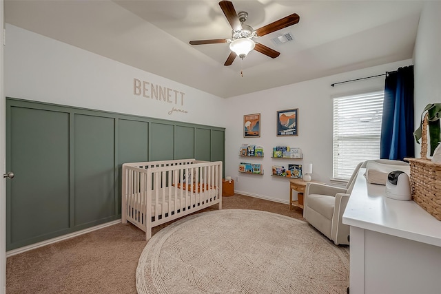 bedroom featuring light carpet, visible vents, ceiling fan, and a nursery area