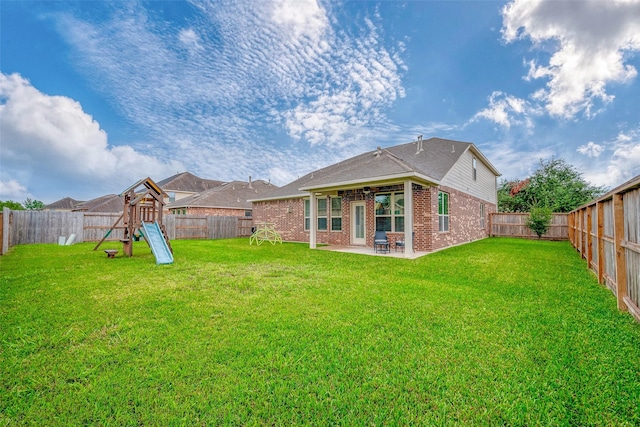 back of property with a lawn, a patio, a fenced backyard, a playground, and brick siding