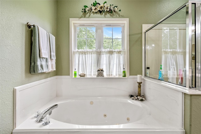 full bathroom with a jetted tub and a textured wall