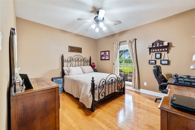 bedroom featuring light wood finished floors, baseboards, a textured ceiling, a ceiling fan, and access to outside