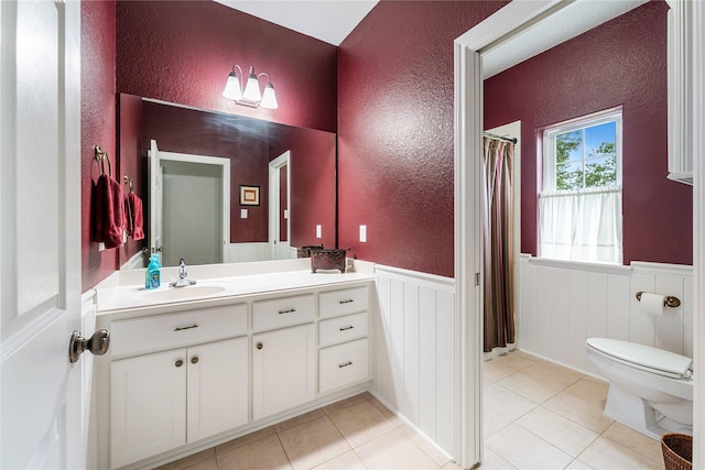 full bathroom featuring a wainscoted wall, toilet, and a textured wall