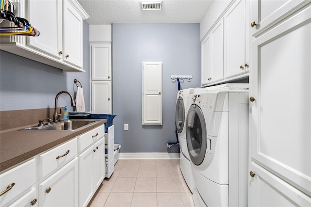 laundry area featuring visible vents, a sink, washing machine and dryer, cabinet space, and light tile patterned flooring