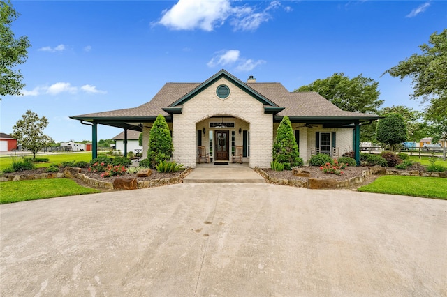 view of front of property featuring roof with shingles, ceiling fan, a chimney, a front lawn, and brick siding