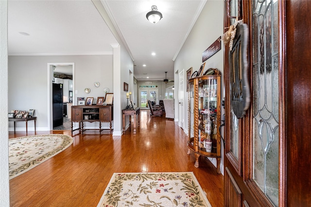 foyer entrance featuring ornamental molding, ceiling fan, baseboards, and wood finished floors