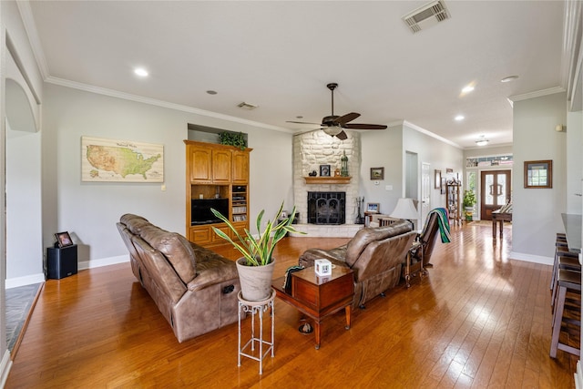 living area with hardwood / wood-style flooring, a fireplace, visible vents, and baseboards