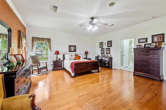 bedroom featuring visible vents, light wood-style flooring, and ornamental molding