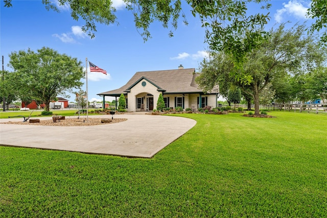 view of front of home featuring brick siding, a front lawn, a chimney, and driveway