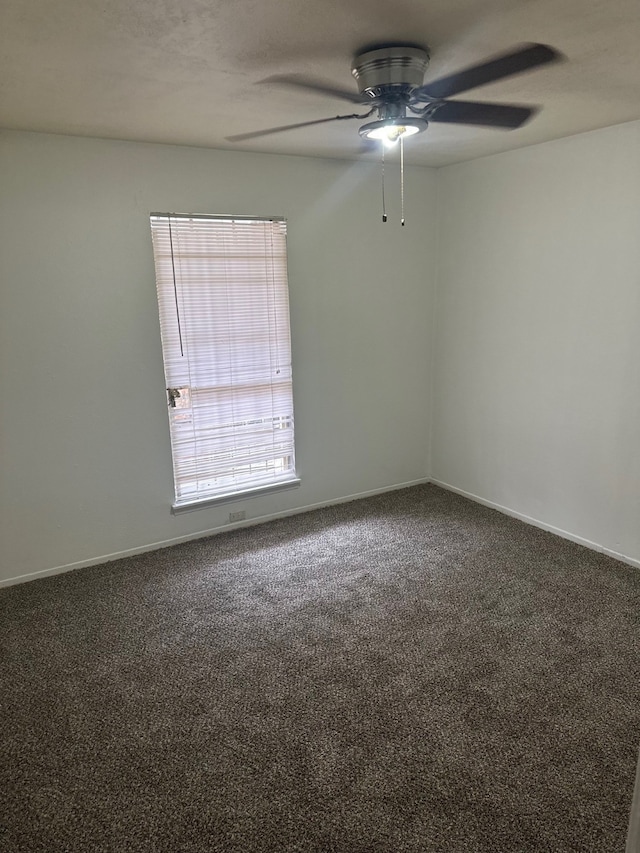 carpeted empty room featuring baseboards and a ceiling fan