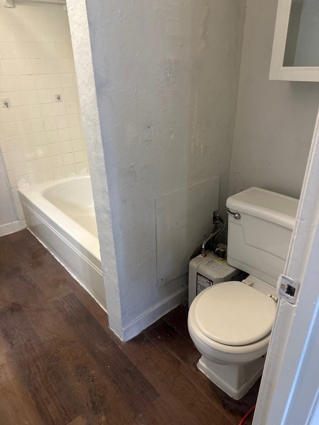 bathroom featuring a textured wall, a washtub, toilet, and hardwood / wood-style flooring