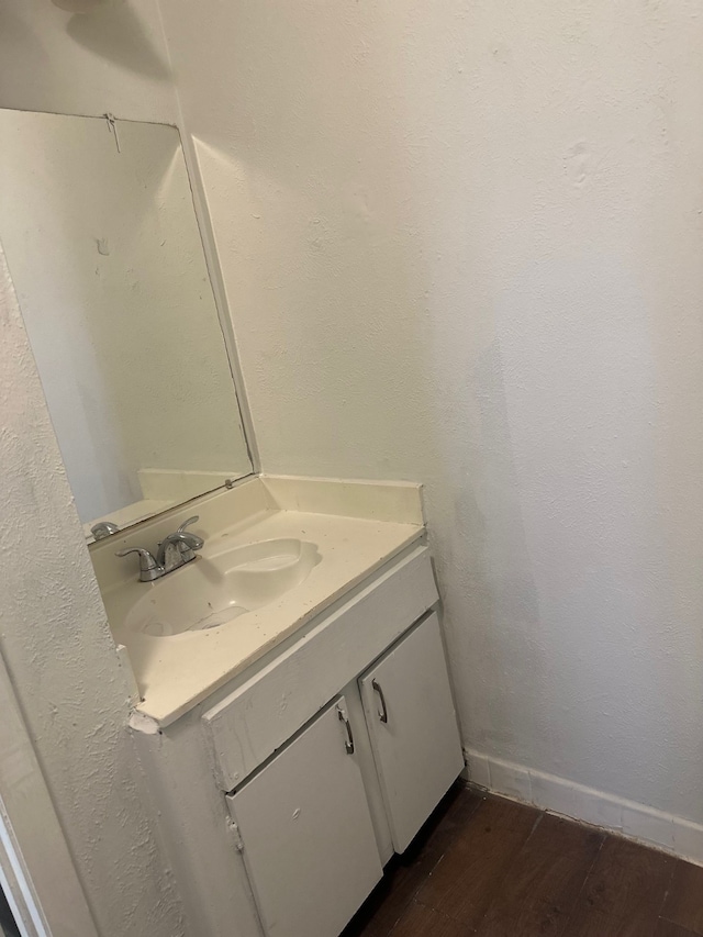 bathroom with baseboards, wood finished floors, and vanity