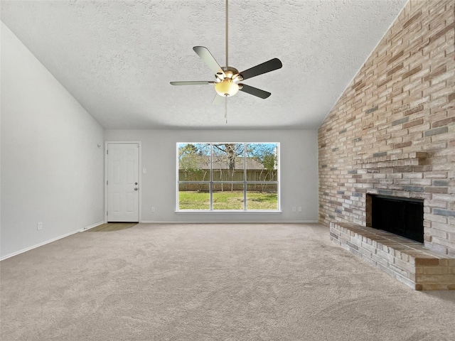 unfurnished living room with a ceiling fan, vaulted ceiling, a textured ceiling, a brick fireplace, and carpet flooring