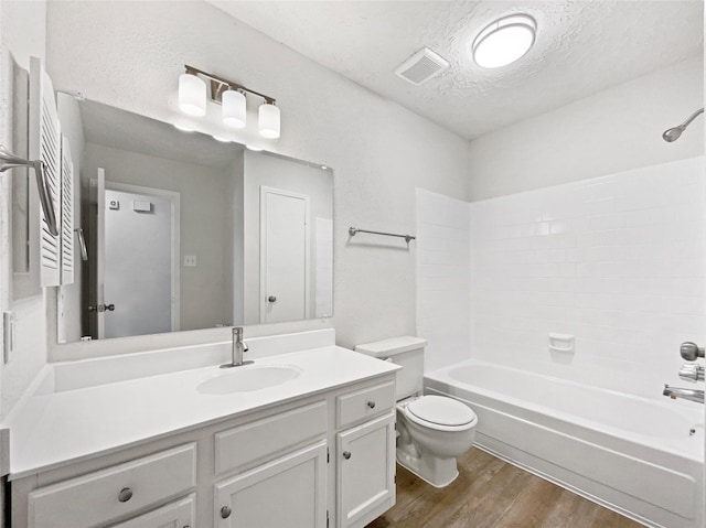 full bath with visible vents, toilet, a textured ceiling, wood finished floors, and vanity