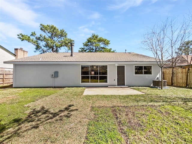 rear view of property featuring a lawn, central AC, fence, roof with shingles, and a patio area