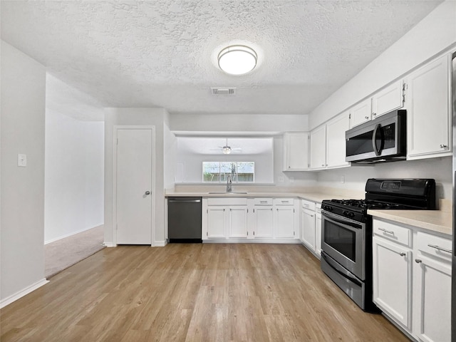 kitchen featuring stainless steel appliances, light wood finished floors, visible vents, and light countertops