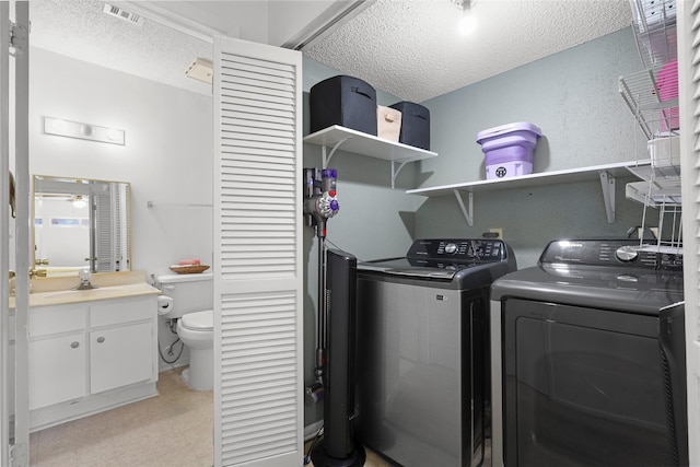 washroom featuring visible vents, laundry area, separate washer and dryer, a sink, and a textured ceiling