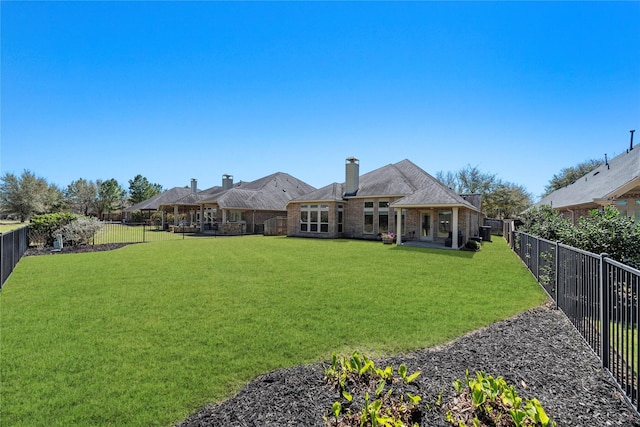 back of house with a lawn, a fenced backyard, and brick siding