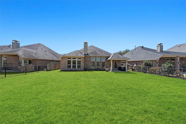 rear view of house featuring a lawn, a chimney, a fenced backyard, and brick siding