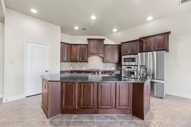 kitchen with tasteful backsplash, visible vents, dark brown cabinets, dark stone countertops, and stainless steel appliances