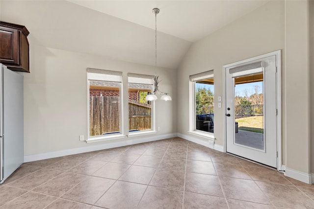 unfurnished dining area featuring light tile patterned floors, a notable chandelier, baseboards, and vaulted ceiling