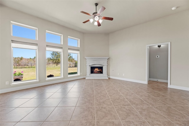 unfurnished living room featuring light tile patterned floors, baseboards, and a warm lit fireplace