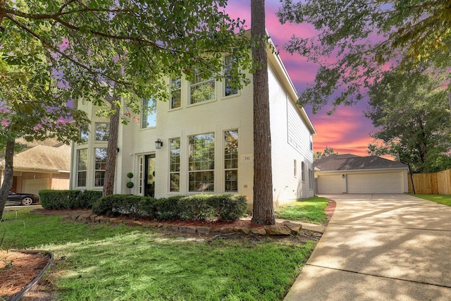 view of front of property with driveway, a front lawn, an outdoor structure, and fence