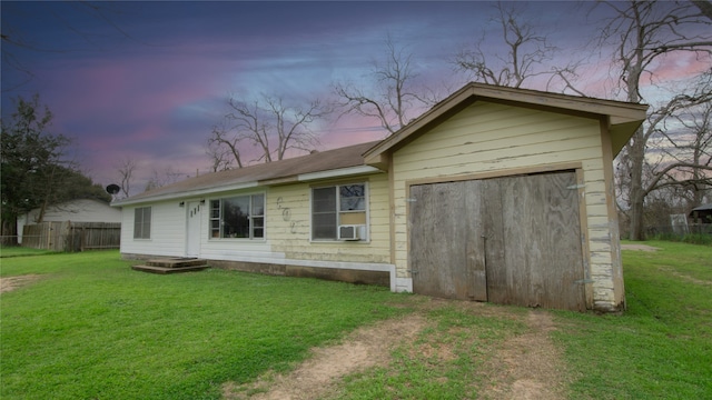 back of house at dusk featuring cooling unit, fence, driveway, a yard, and a garage