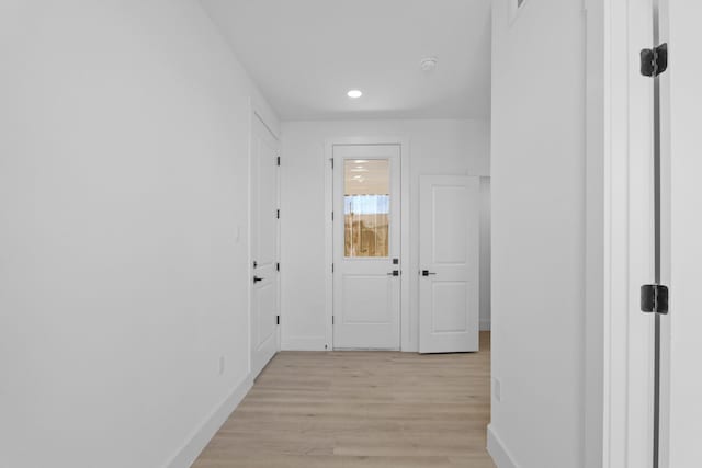 corridor with light wood-type flooring and baseboards