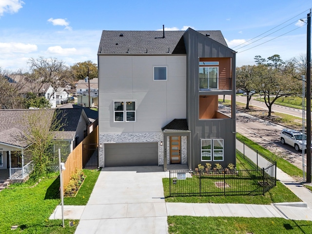 contemporary house with driveway, a front lawn, a fenced front yard, board and batten siding, and a garage