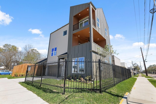 view of side of home featuring a lawn, board and batten siding, and a fenced front yard