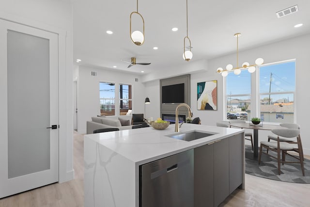 kitchen featuring visible vents, a sink, hanging light fixtures, dishwasher, and modern cabinets