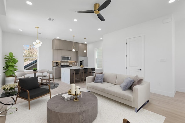 living room with light wood finished floors, recessed lighting, a ceiling fan, and baseboards