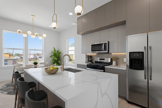 kitchen with light wood finished floors, a sink, gray cabinetry, stainless steel appliances, and modern cabinets