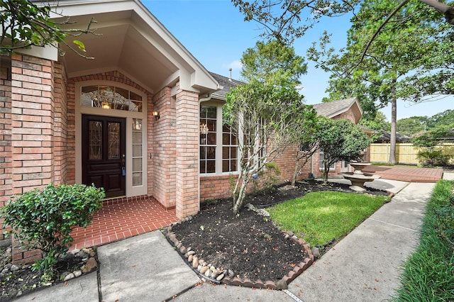 property entrance with fence, brick siding, french doors, and a shingled roof