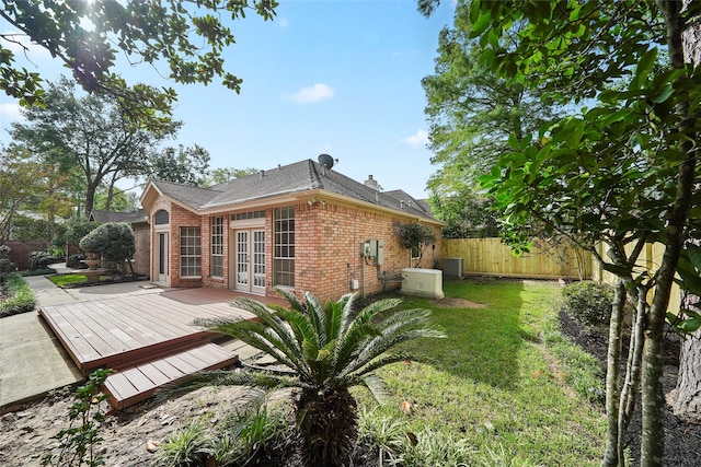 rear view of house with fence, a wooden deck, a chimney, french doors, and brick siding