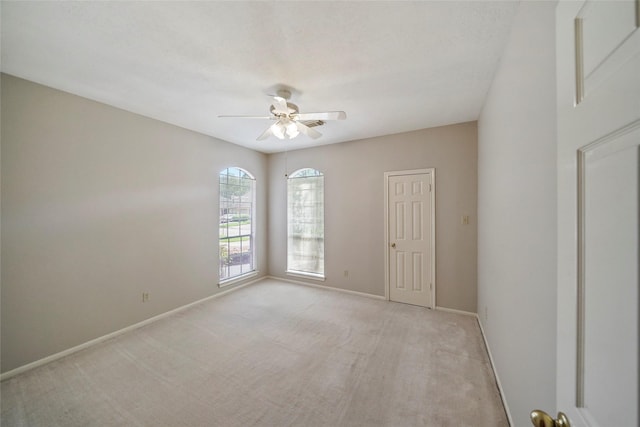 empty room with baseboards, light carpet, and ceiling fan